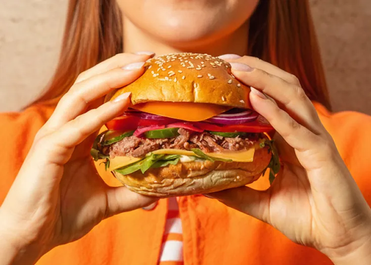 Burger z menu Foodify trzymany w dłoniach